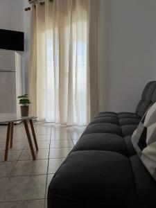 a living room with a black couch in front of a window at Starry Coast Apartments in Nea Potidaea