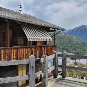 a wooden house with a fence in front of it at Gîte de Mase sur la rive droite du Val d'Hérens in Mase