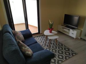 Rua GALICIA في أغواردا: غرفة معيشة مع أريكة زرقاء وتلفزيون
