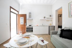 a white living room with a table and a couch at Centrale Lefkada old town in Lefkada Town