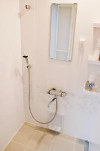 La salle de bains blanche est pourvue d'une douche et d'une fenêtre. dans l'établissement Minpaku Yorozuya - Vacation STAY 12905, à Kurayoshi