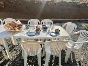 ein weißer Tisch mit Stühlen und ein Korb mit Brot in der Unterkunft Chambre double indépendante BALI au sein du domaine PASSELOUP in Liergues
