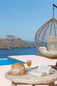 a table with a book and a glass of orange juice at Nisides Suites in Livadi Astypalaias