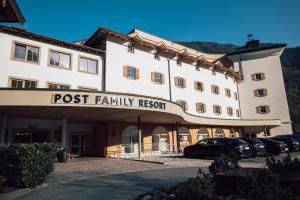 ein Postfamilien-Resortgebäude mit vor der Tür geparkt in der Unterkunft POST Family Resort in Unken