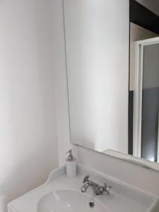 ein weißes Badezimmer mit einem Waschbecken und einem Spiegel in der Unterkunft Chambre double indépendante NATURALE au sein du domaine PASSELOUP in Liergues