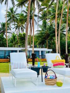 2 sillas y una mesa en un patio con palmeras en Coral Beach Cabana -- Eco Adventure Beach Villa On 3km Beach, en Savusavu