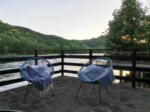 two chairs with blue cushions sitting next to a river at Kutak na Drini in Ljubovija