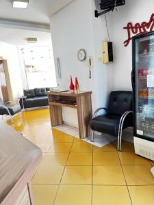 uma sala de espera com uma mesa e cadeiras e uma televisão em Tropical Palace Hotel em Lavras