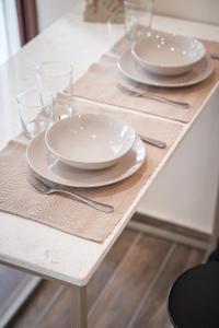 a table with white plates and glasses on it at LP Luxury Suite - Old Town Xanthi in Xanthi