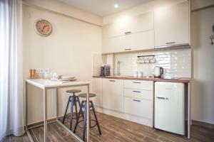 a kitchen with white cabinets and bar stools at LP Luxury Suite - Old Town Xanthi in Xanthi