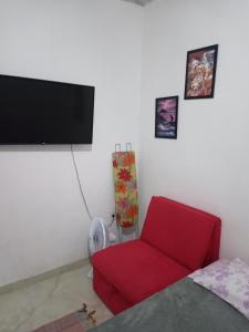 a living room with a red chair and a flat screen tv at kitnet Maysa em Benfica RJ in Rio de Janeiro