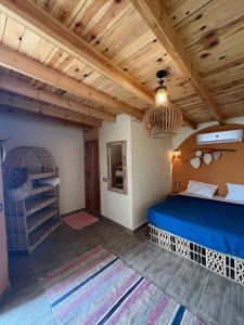 a bedroom with a blue bed and a wooden ceiling at Habiba Beach Lodge in Nuweiba