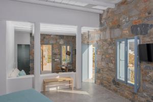 a bedroom with a stone wall with a tv on it at Nisides Suites in Livadi Astypalaias