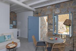 a living room with a stone wall and a table and chairs at Nisides Suites in Livadi Astypalaias
