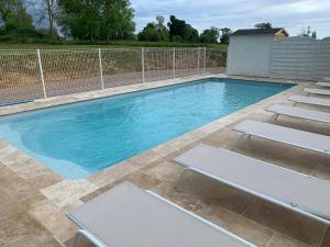 - une piscine avec trois chaises longues devant dans l'établissement gîte du parc du moulin du pré, à Bavent