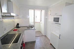 a white kitchen with a sink and a microwave at Ático en la playa de Muchavista de El Campello con vistas espectaculares a playa San Juan in El Campello