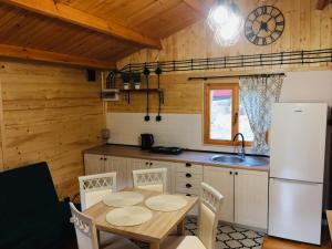 a kitchen with a table and a white refrigerator at Domki letniskowe przy lesie - "U Łastka" in Bartołty Wielkie