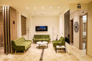 a living room with two green couches and a table at Luciana Hotel by BRATUS in Aqaba