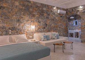 a bedroom with a bed and a stone wall at Nisides Suites in Livadi Astypalaias +53 photos