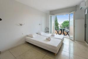 Biała sypialnia z łóżkiem i balkonem w obiekcie Appartement de Madrid - Welkeys w Cannes