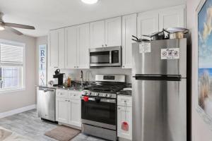 a kitchen with white cabinets and a stainless steel refrigerator at Beach Block Parking Modern Decor Porch in Brigantine