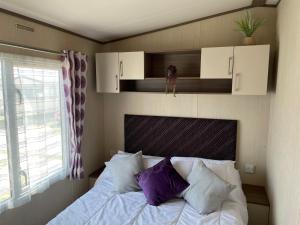 een slaapkamer met een bed met paarse en witte kussens bij PK Holiday Home in Great Yarmouth