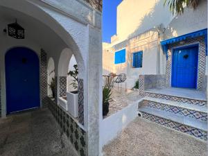 - une porte bleue dans un bâtiment blanc avec des escaliers dans l'établissement OLIVIA Guest House (Eya & Abbes), à Sidi Bou Saïd