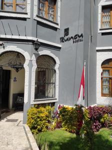 a building with a flag and flowers in front of it at Runcu Arequipa in Arequipa