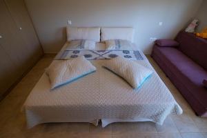 a bedroom with a white bed with a purple couch at Sunset Resort in Aiándion