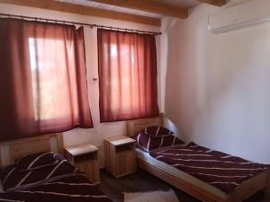 twee bedden in een kamer met rode gordijnen bij Tómajor Vendégházak in Tiszaeszlár