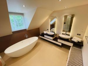 ein großes Badezimmer mit zwei Waschbecken und einer großen Badewanne in der Unterkunft Côté Malmedy in Malmedy