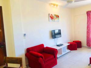ein Wohnzimmer mit einem roten Stuhl und einem TV in der Unterkunft Maamoura Beach apartment in Alexandria