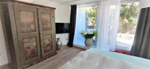 a bedroom with a large wooden cabinet and a vase of flowers at Bel giardino in Friedrichshafen