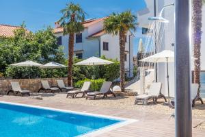 een zwembad met stoelen en parasols naast een gebouw bij Apartments Petra Krk in Krk