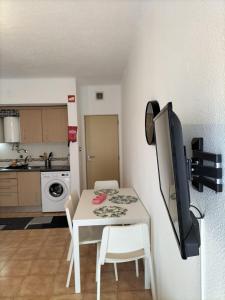 eine kleine Küche mit einem weißen Tisch und einem Fernseher in der Unterkunft Apartamento Maria do Céu Villa Magna in Albufeira
