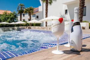 a bottle of champagne with a strawberry in a glass next to a swimming pool at Apartments Petra Krk in Krk