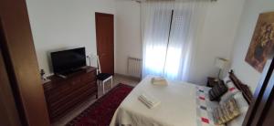 Kleines weißes Zimmer mit einem TV und einem Bett. in der Unterkunft La Badia del Cavaliere 2 in Rom