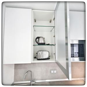 a kitchen with white cabinets and a toaster oven at Le Vallaya Suites & Spa in Menton