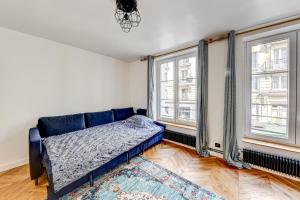 uma sala de estar com um sofá azul e duas janelas em PANTHEON em Paris