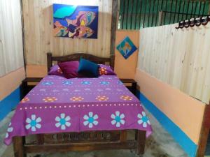 a bedroom with a bed with a purple comforter at Ecohotel Arte y Aventura in Isla Grande