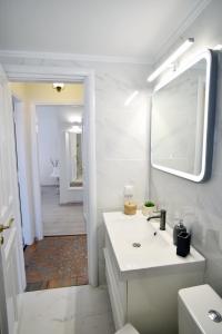 a white bathroom with a sink and a mirror at Kallisti the house at the port in Galaxidhion