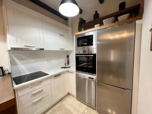 uma cozinha com armários brancos e um frigorífico de aço inoxidável em Preciosa casa marinera en Carril em Vilagarcia de Arousa