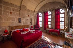 a bedroom with a red bed in a stone room at Cappadocia Antique Gelveri Cave Hotel in Guzelyurt
