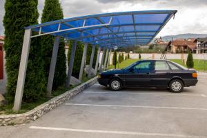 um carro estacionado num parque de estacionamento com um dossel azul em Motel Dani em Nova Bila