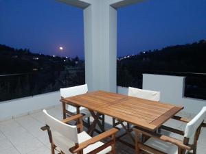 a wooden table and chairs on a balcony at night at View house, Platana Kymi Evoia in Platána