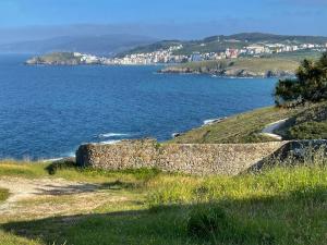 a stone wall on a hill next to a body of water at Malpica Vistas in Malpica