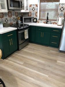 a kitchen with green cabinets and a stove top oven at Modern Spanish Villa- Pool- By River-Tropical !!! in Fort Lauderdale