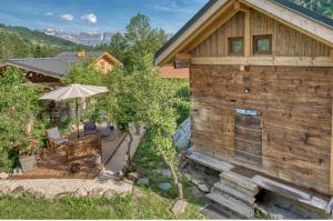 a wooden cabin with a table and an umbrella at Mazot savoyard situé à 25 kms de CHAMONIX in Saint-Gervais-les-Bains