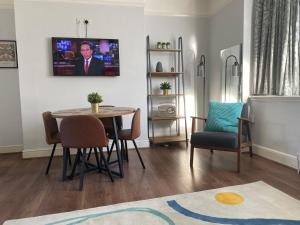 a living room with a table and chairs and a tv at Invicta Apartment in Ashford