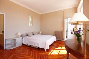 Un dormitorio con una cama y una mesa con un jarrón de flores en Magnifique appartement d'époque avec Vue Mer 4 personnes avec terrasse Le Port Nice en Niza